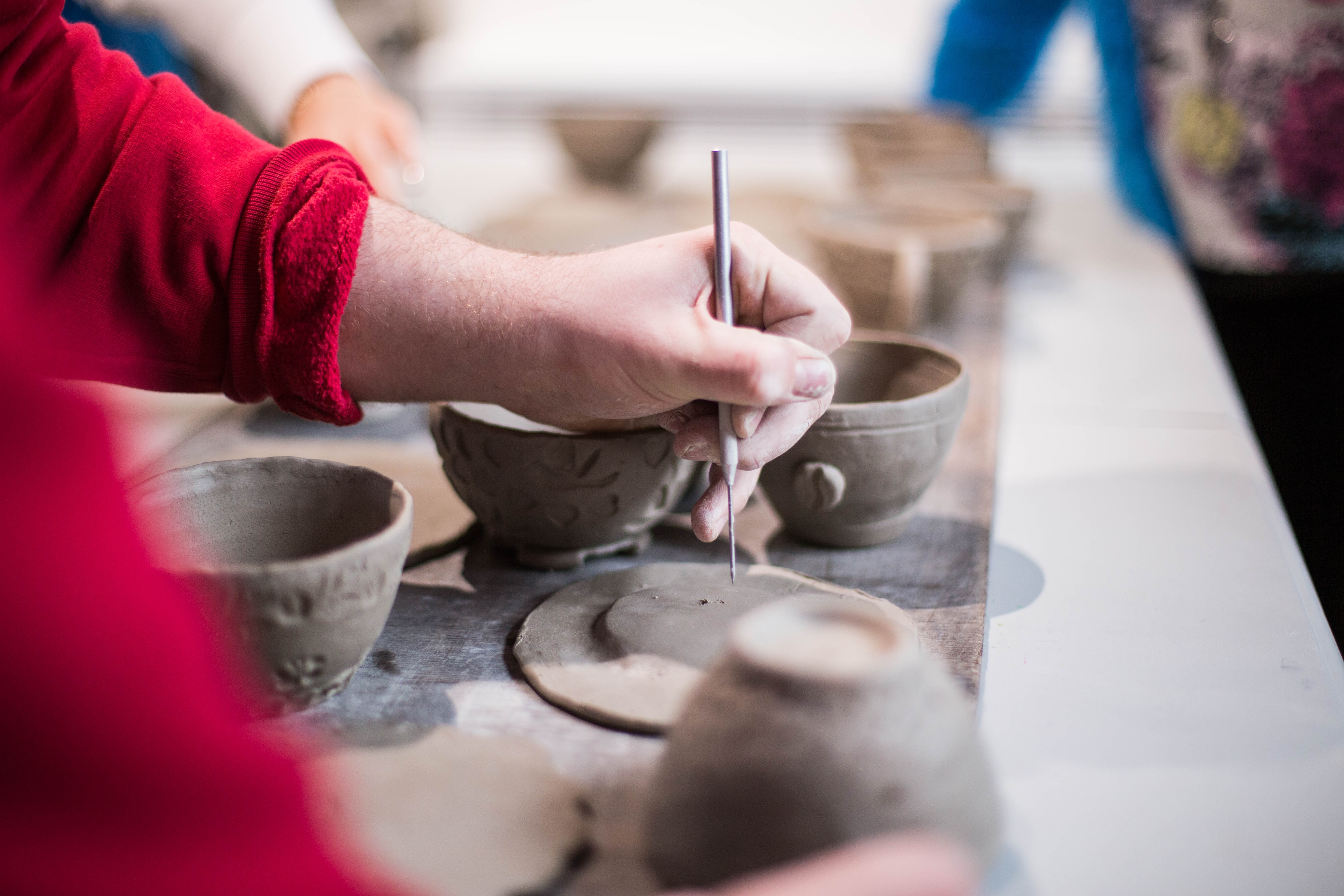 Person hand-building a clay bowl