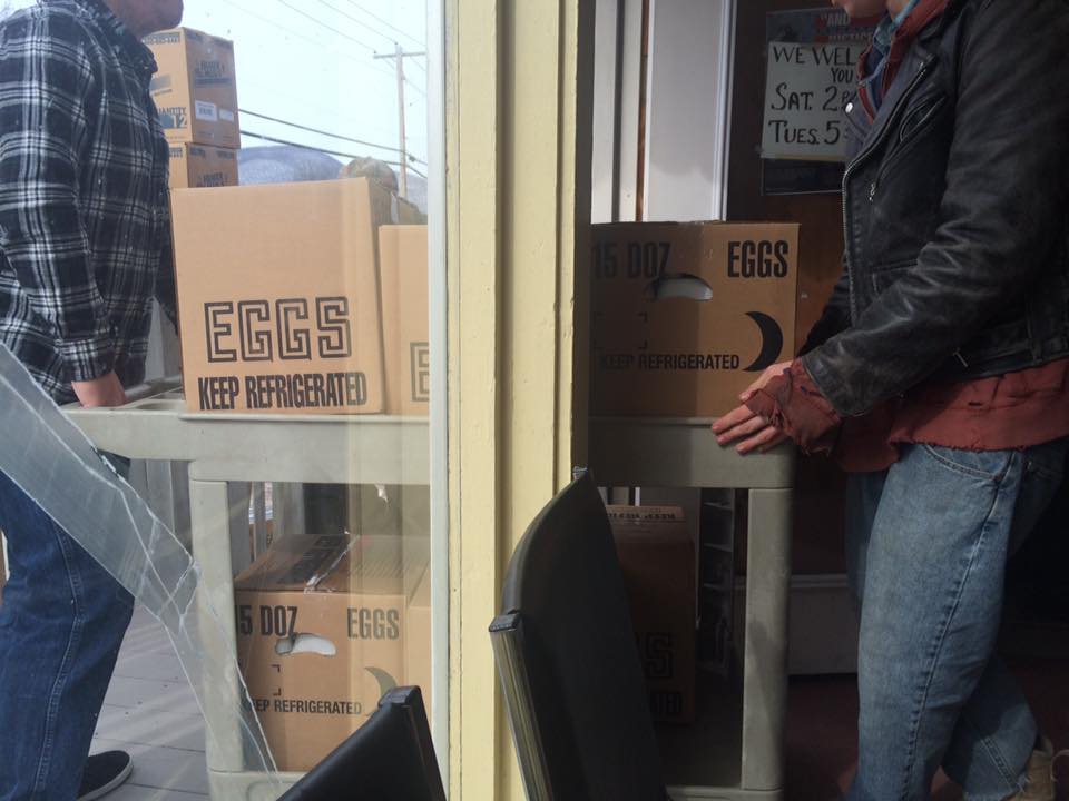 Two men load boxes of eggs onto a cart as GBICS volunteer food drivers